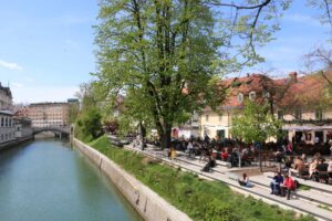 Ljubljanica River promenade with trees and outdoor cafés on a Ljubljana mountain biking tour in Slovenia