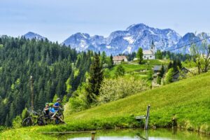 Mountain biker descending through alpine meadows in Podolševa on a Kamnik–Savinja Alps mountain bike adventure in Slovenia