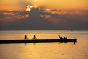 Cyclists riding along the Piran seaside at sunset on a Trans Slovenia mountain biking tour