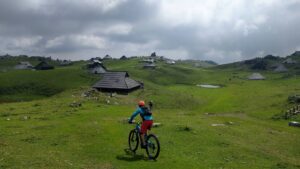Mountain biker cycling past traditional shepherd huts on a Velika Planina MTB tour in Slovenia