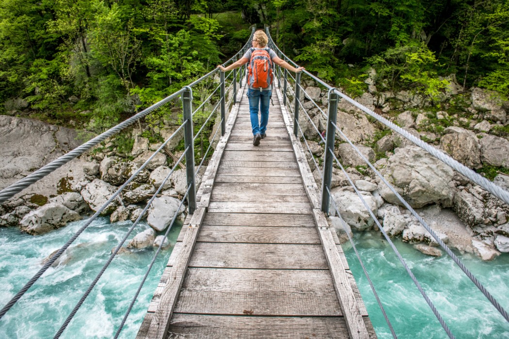 Crossing the wooden suspension bridge over Soča River at the Walk of Peace Hiking tour