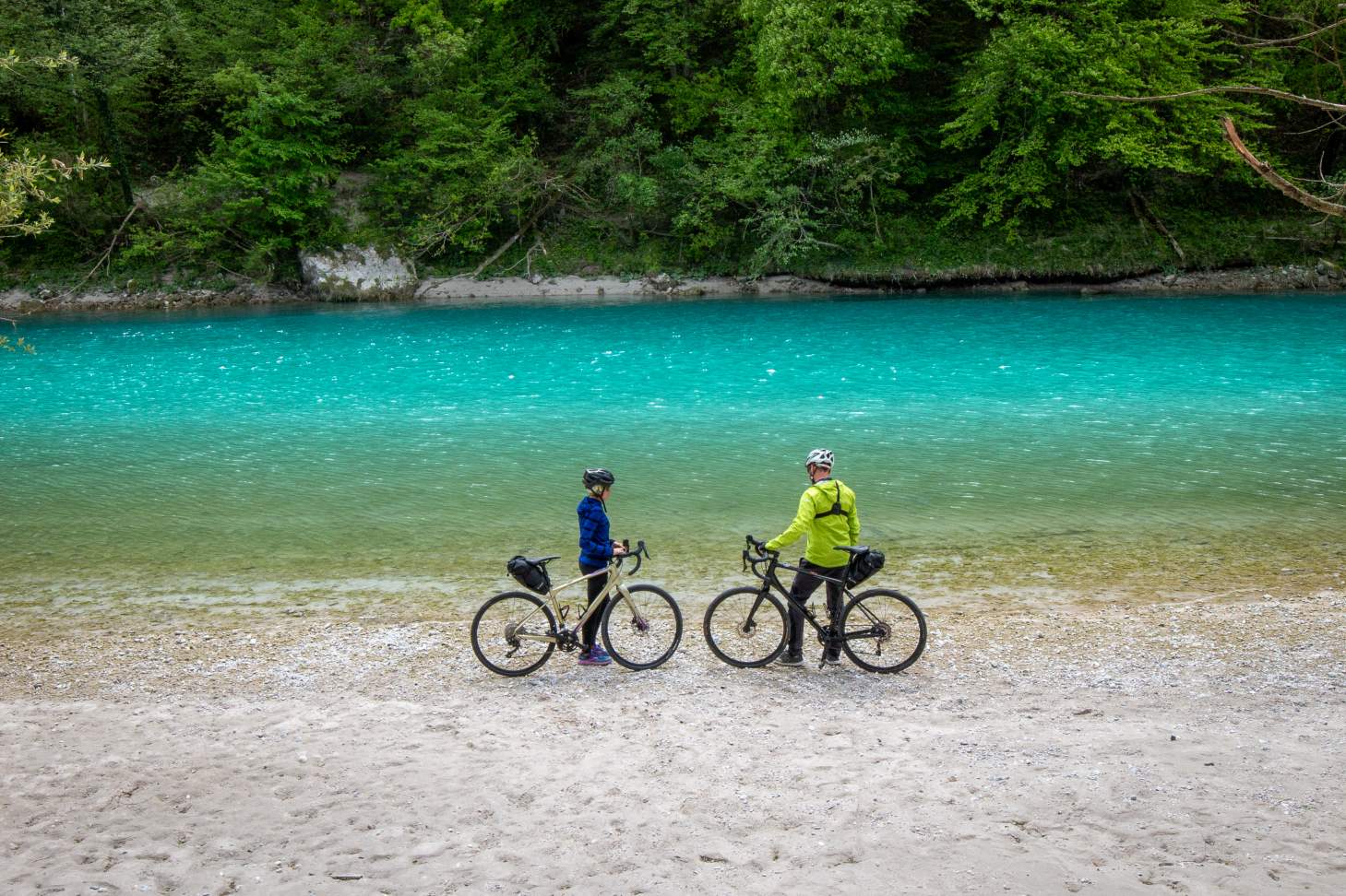 Two cyclists along the shore of Soča River in Slovenia during the Trans Dinarica tour
