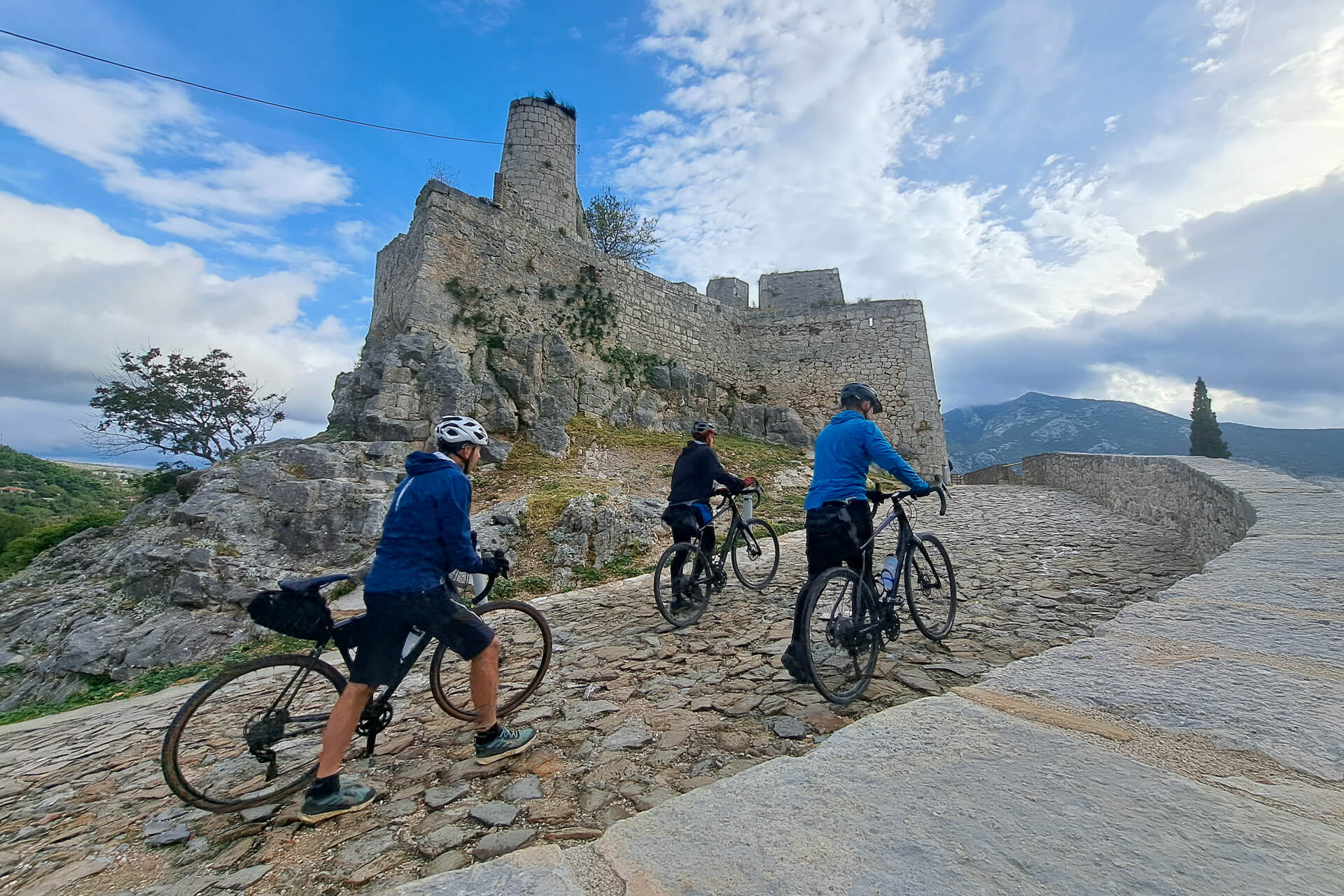 Cyclists pushing bikes to visit Klis fortress near Split, Croatia.
