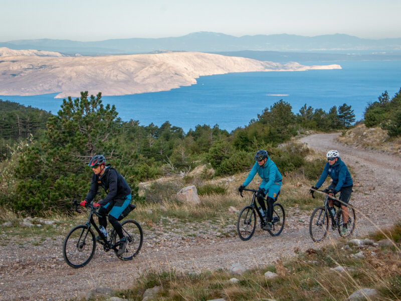 Cyclists on gravel bikes riding from Senj to Velebit with islands in the background.