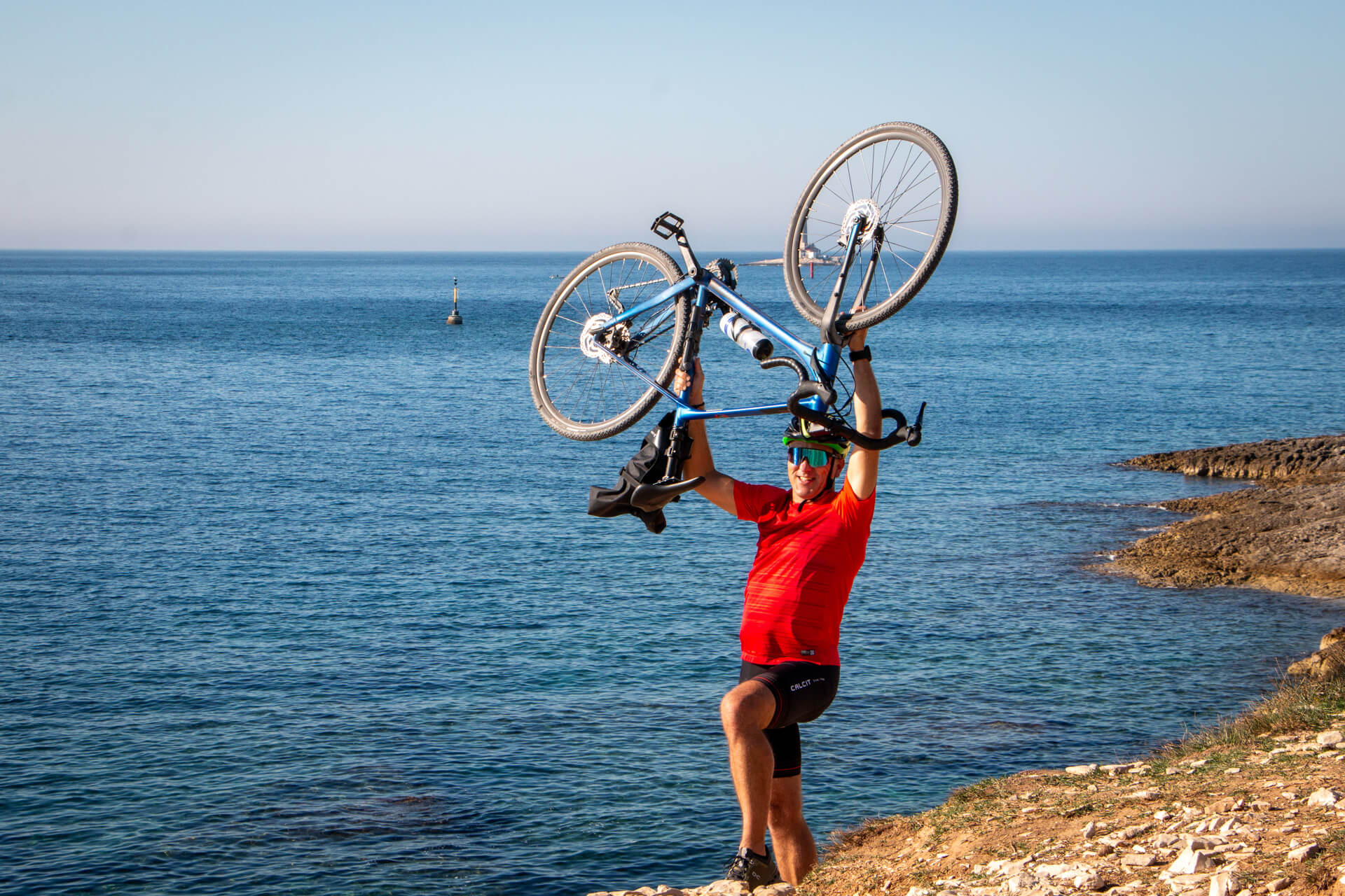 Cyclists lifting his gravel bike up in the air.