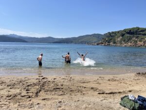Mountain bikers enjoying a swim at a sandy beach during an MTB tour on Elba Island