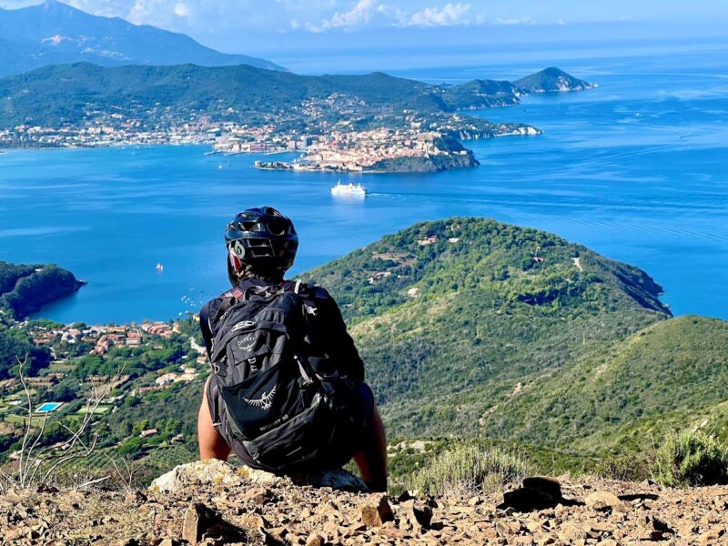Mountain biker overlooking Elba’s coastline during a mountain biking trip in Europe