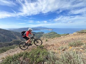 Biker riding a rocky trail with coastal views during a mountain bike trip on Elba, Italy