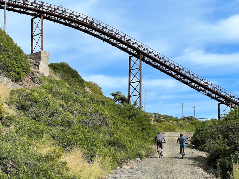 Mountain bikers following a grassy trail beneath an old bridge on Elba Island
