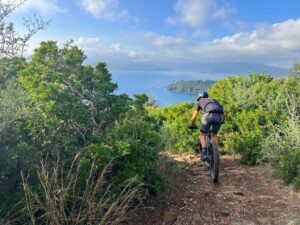 Mountain biker following a coastal trail during a guided MTB tour in Tuscan island
