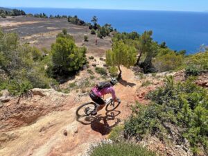 Mountain biker descending a rocky coastal trail while mountain biking on Elba Island in Tuscany