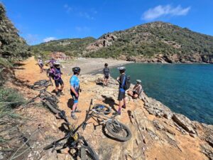 Mountain bikers taking a break with their bikes on the rocky shore of Ortano Beach, Italy
