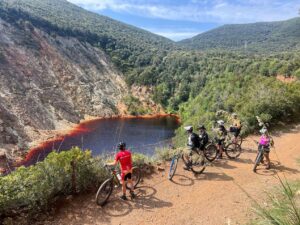 Bikers overlooking the Red Lake during a mountain biking tour on Elba in Tuscany